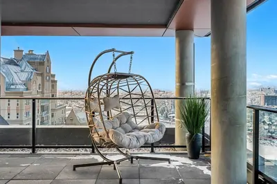 a rattan chair sitting on top of a balcony at Dt Spacious and Vibrant | Kng Bed| Outdoor patio in Calgary