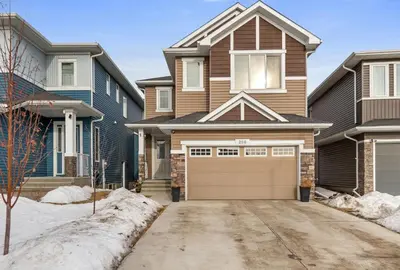 a house with a garage in the snow at Brand New 3 Bedroom, 2 Washroom, Kitchen and Ensuite in Chestermere