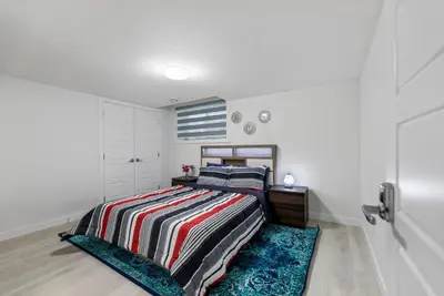 a bedroom with a bed with a striped blanket at Brand New 3 Bedroom, 2 Washroom, Kitchen and Ensuite in Chestermere