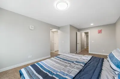 a bedroom with a large bed with a blue blanket at Brand New Modern Home - 5 Beds - Office - Garage - Luxury Living - Sleeps 9 in Calgary