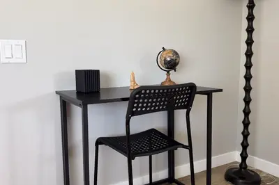 a black desk with a chair next to a wall at Newly Renovated, Bright & Cozy 3 bdrm Home - 6min from Rogers Arena in Edmonton