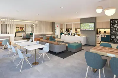 a restaurant with tables and chairs in a cafeteria at TownePlace Suites by Marriott Victoria Airport Sidney in Sidney