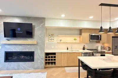 a kitchen with a fireplace and a tv on the wall at Canmore Peaks Retreat | Luxe 1BR w Pool & Gym in Canmore