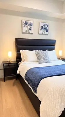 a bedroom with a large bed with blue and white pillows at Canmore Peaks Retreat | Luxe 1BR w Pool & Gym in Canmore