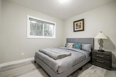 a bedroom with a bed with a lamp and a window at Renovated 3BE, 2BA close to UoC, downtown, SAIT in Calgary
