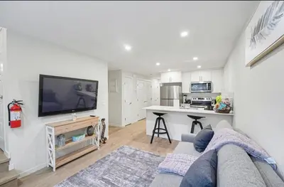 a living room with a couch and a tv and a kitchen at Luxury brand new 1 Bedroom Townhome in Calgary