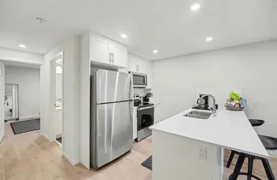 a white kitchen with a refrigerator and a counter at Luxury brand new 1 Bedroom Townhome in Calgary
