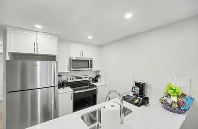 a kitchen with a stainless steel refrigerator and white cabinets at Luxury brand new 1 Bedroom Townhome in Calgary