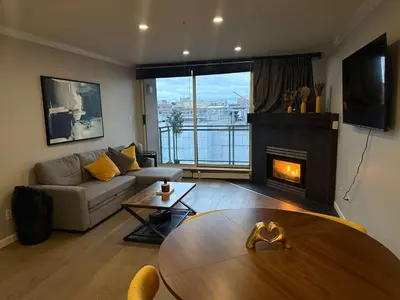 a living room with a table and a fireplace at Extra Spacious with a King Bed Sauna Pool & Jacuzzi in Vancouver