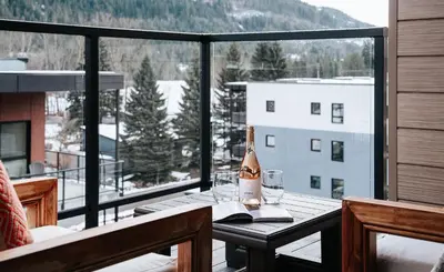 a bottle of wine sitting on a table on a balcony at Cloudscape Penthouse by Revelstoke Vacations in Revelstoke