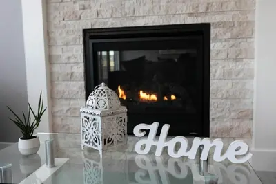 a fireplace with a candle on top of a glass table at Scenic Cochrane Family Home in Cochrane