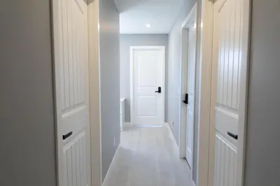 a hallway with a white door and a white floor at Scenic Cochrane Family Home in Cochrane