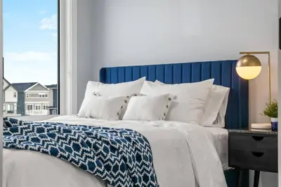 a large bed with a blue headboard and white pillows at Modern 4BR Retreat 3 Baths Near to Banff&Airport in Calgary