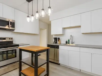 a kitchen with white cabinets and a wooden table at Cozy 2BR 1BA Retreat in Vibrant Vancouver in Vancouver