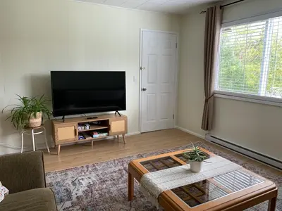 a living room with a flat screen tv and a table at Hidden JEM - Your Home Away From Home in Coal Harbour