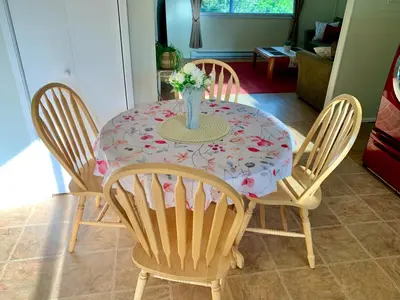 a table with four chairs and a vase of flowers on it at Hidden JEM - Your Home Away From Home in Coal Harbour