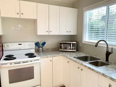 a kitchen with white cabinets and a stove and a sink at Hidden JEM - Your Home Away From Home in Coal Harbour