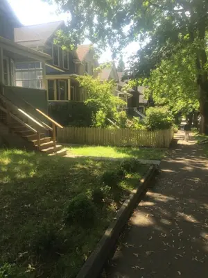 a residential yard with a house and a fence at Quiet-comfy 3 bedroom house on a tree lined street in Kitsilano in Vancouver