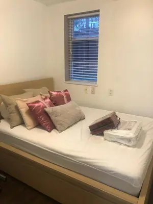 a bed with white sheets and pillows on it at Quiet-comfy 3 bedroom house on a tree lined street in Kitsilano in Vancouver