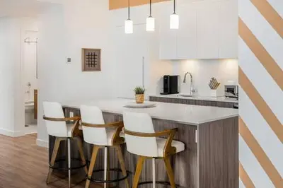 a kitchen with a island with white counter tops and chairs at Spacious and elegant| 2 Kng Beds| Space for all in Calgary