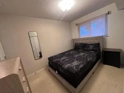 a small bedroom with a bed and a window at Cozy West Edmonton Home Near Jasper Park & shops in Edmonton