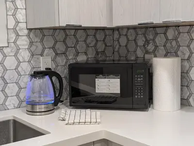 a microwave oven sitting on a counter in a kitchen at Modern 2BR Suite Steps to SkyTrain in Vancouver