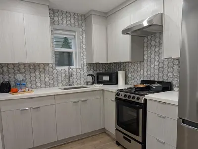 a kitchen with white cabinets and a stove top oven at Modern 2BR Suite Steps to SkyTrain in Vancouver