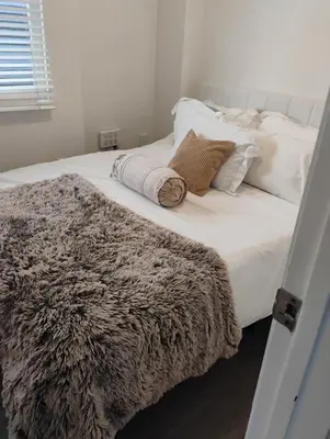 a large white bed with a furry blanket on it at Quiet-comfy 3 bedroom house on a tree lined street in Kitsilano in Vancouver