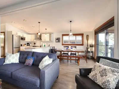 a living room with a blue couch and a kitchen at Wickham's Wake - 3BR Oceanfront - pet friendly in Port Renfrew