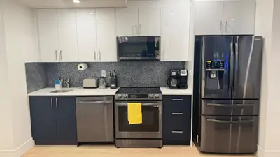 a kitchen with stainless steel appliances and white cabinets at Modern 1BR Private Suite NW Near Airport & Amazing Shopping! Free Netflix, Parking! in Calgary