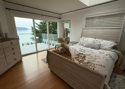 a bedroom with a large bed and a large window at Woodhaven - Entire Home, Ocean Front in Bowser