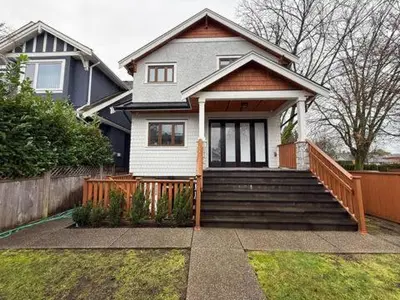 a white house with a wooden fence and stairs at YVR3106 | Cozy 3BR in Central Vancouver | 15 min to Downtown in Vancouver