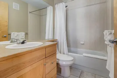 a bathroom with a sink and a toilet and a tub at Stylish Mountain View Condo with Gym in Canmore