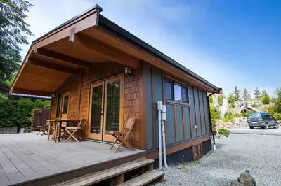 a tiny house with a porch and a deck at Explorer's Retreat Sauna & Bunkhouse & Fire pit in Port Renfrew