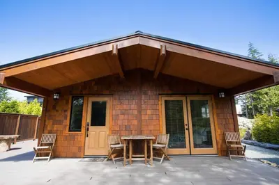 a house with a patio with a table and chairs at Explorer's Retreat Sauna & Bunkhouse & Fire pit in Port Renfrew