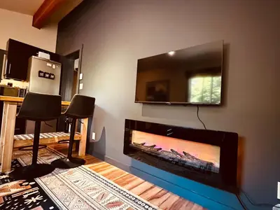 a living room with a fireplace and a flat screen tv at Hot Tub - Large Fully Enclosed deck - Pet Friendly in Port Renfrew