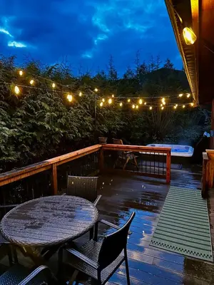 a patio with a table and chairs at night at Hot Tub - Large Fully Enclosed deck - Pet Friendly in Port Renfrew