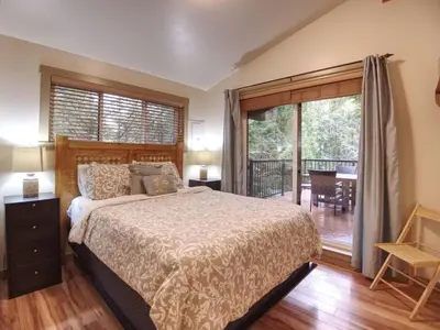 a bedroom with a large bed and a balcony at Hot tub Oasis Among Trees - Pet Friendly in Port Renfrew