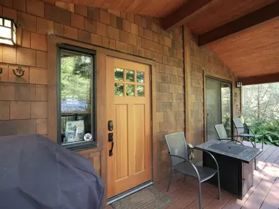 a front door of a house with a table and chairs at Hot tub Oasis Among Trees - Pet Friendly in Port Renfrew
