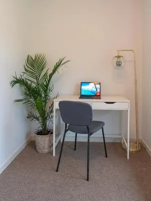 a desk with a laptop computer on it next to a plant at Cozy Large Family Home near Lake, AC, Full Kitchen in Calgary