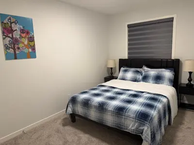a bedroom with a bed with a blue and white plaid blanket at Cozy 3 beds 2 and half baths 2 Story Home in Calgary