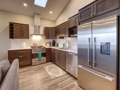 a kitchen with stainless steel appliances and wooden cabinets at Amazing Marina & Oceanfront View - Pet Friendly - Sleeps 6 in Port Renfrew
