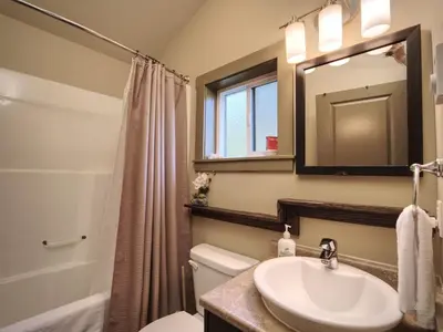 a bathroom with a sink and a toilet and a mirror at Hot Tub - Pet Friendly - Cozy Escape with Fire Pit in Port Renfrew