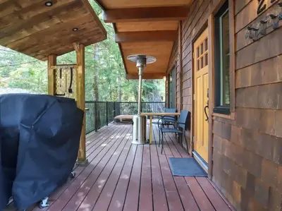 a large deck with a table and chairs on it at Hot Tub - Pet Friendly - Cozy Escape with Fire Pit in Port Renfrew