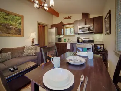 a kitchen and living room with a table with plates on it at Hot Tub - Pet Friendly - Cozy Escape with Fire Pit in Port Renfrew