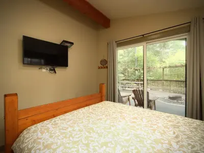 a bedroom with a bed and a flat screen tv at French Girl's Lair - Pet Friendly - Garden View in Port Renfrew