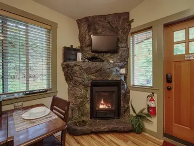 a fireplace in a living room with a table and a tableablish at French Girl's Lair - Pet Friendly - Garden View in Port Renfrew