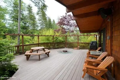 a wooden deck with two chairs and a picnic table at French Girl's Lair - Pet Friendly - Garden View in Port Renfrew
