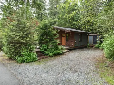 a small cabin in the middle of a forest at French Girl's Lair - Pet Friendly - Garden View in Port Renfrew