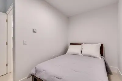 a white bedroom with a bed with two pillows at Spacious Apartment Fully Equipped in Prime Location in Vancouver